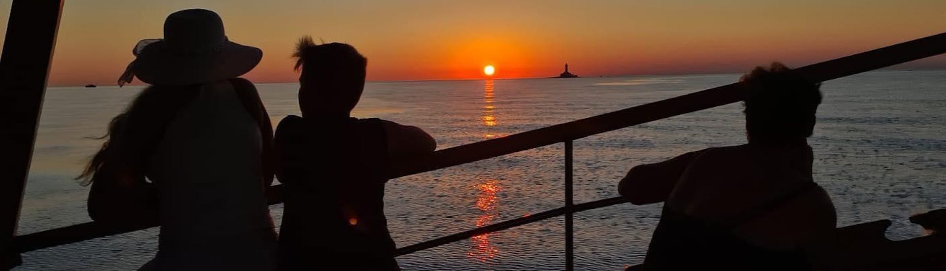 Menschen beobachten den Sonnenuntergang während der Bootstour zur Delfinbeobachtung bei Sonnenuntergang in Richtung Horizont.
