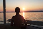 Un homme regarde le coucher de soleil lors d'une balade privée en catamaran dans la baie de Juan-les-Pins avec SeaZen.