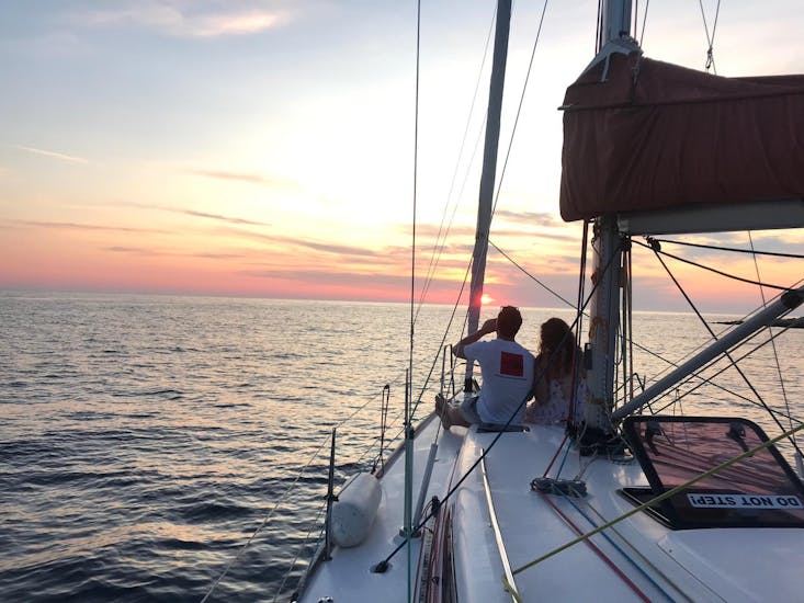 A couple is watching the sunset during a boat trip from Hvar to Cape Pelegrin with The Day Sail Croatia.