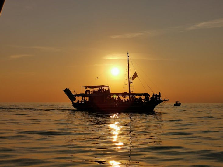 Der Himmel färbt sich während der von Kristofor Boat Excursions Poreč organisierten Bootstour in Poreč mit Delfinbeobachtung bei Sonnenuntergang orange.