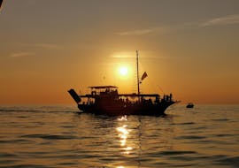 Der Himmel färbt sich während der von Kristofor Boat Excursions Poreč organisierten Bootstour in Poreč mit Delfinbeobachtung bei Sonnenuntergang orange.