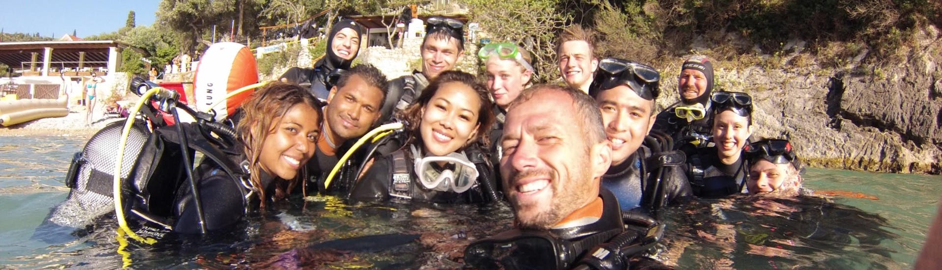 Un gruppo di subacquei e il loro istruttore dell'Achilleon Diving Center di Corfù sorridono alla macchina fotografica mentre entrano in acqua e si preparano ad immergersi a Paleokastritsa.