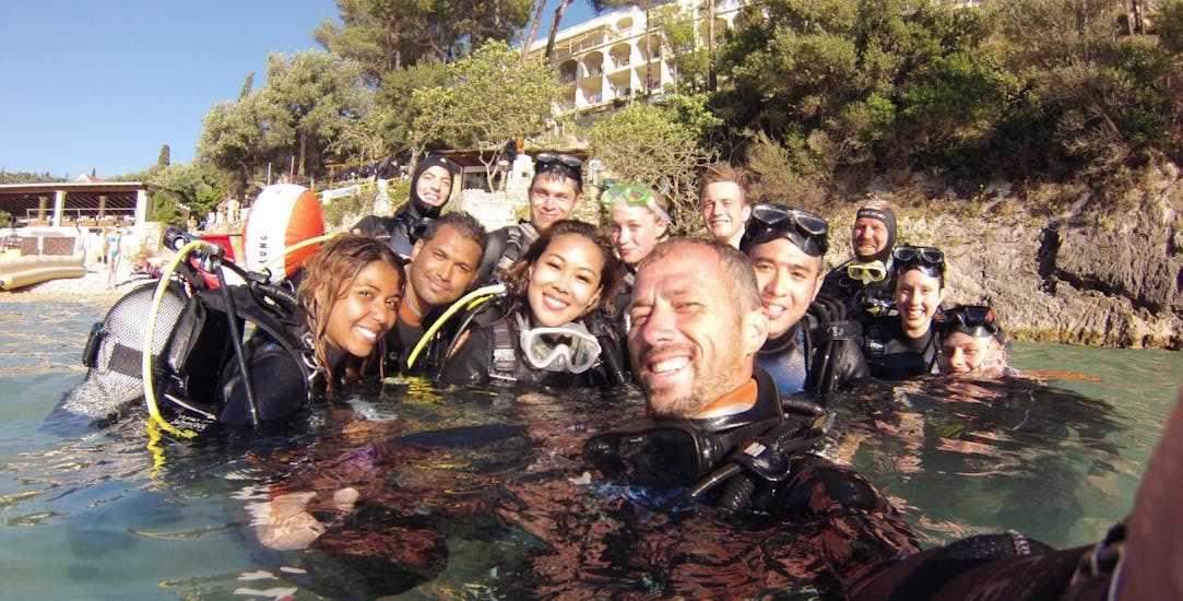 Een duikinstructeur van Achilleon Diving Center Corfu neemt een selfie met een groep mensen die deelnemen aan de PADI Open Water Diver Course in Paleokastritsa for Beginners.