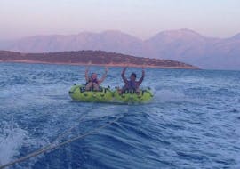 Two people have fun during a towable tube ride in Agios Nikolaos Bay with Pelagos Dive Center Crete.