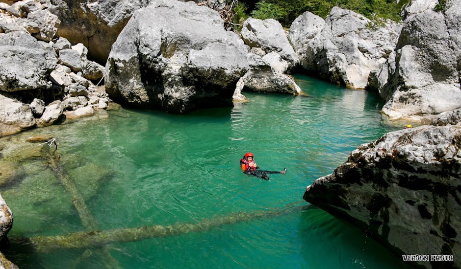 A woman is floating in the river during her River Trekking Tour in Pont de Tusset in Verdon for Families with Feel Rafting.