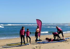 Eine Familie wärmt sich am Strand vor ihrem Surfkurs "Family Package" am Messanges South Beach mit der Messanges Surf School auf.