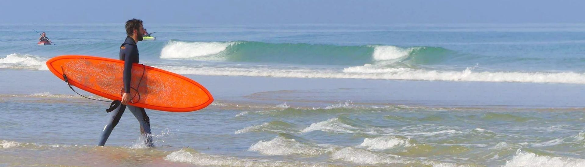 Een surfer gaat naar het water voor zijn privé-surflessen op Messanges South Beach met Messanges Surf School.