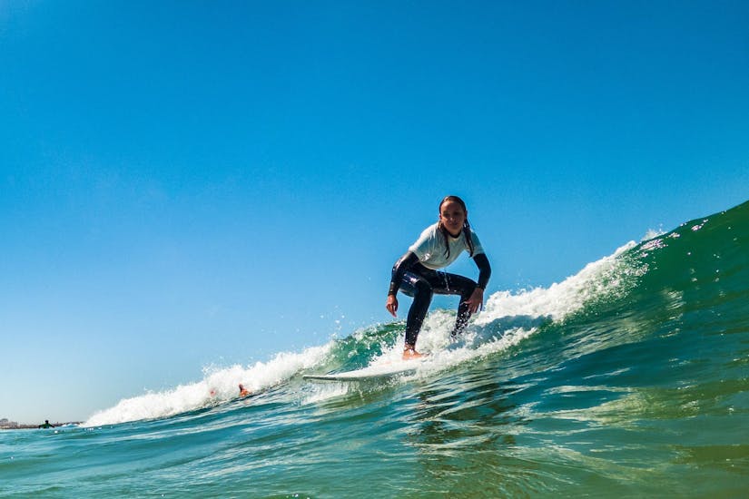 A young girl from the Gecko Surf School in the water surfing on the Costa da Caparica.