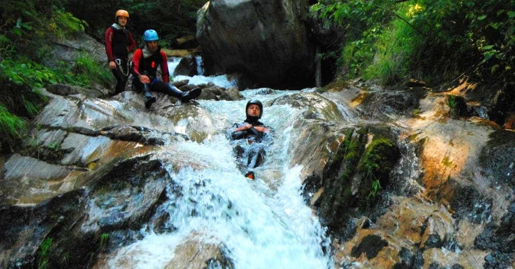 Ein Mann von dem Sporterlebnis Camp Pristavec Obervellach rutscht beim Canyoning einen Wasserfall hinunter.
