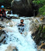 Ein Mann von dem Sporterlebnis Camp Pristavec Obervellach rutscht beim Canyoning einen Wasserfall hinunter.