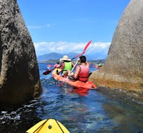 People kayaking between rocks during the Sea Kayaking to the Isolella Peninsula from Porticcio with Cors'Aventure.