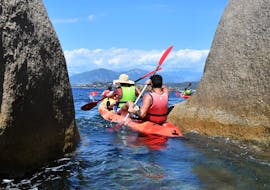 Des personnes faisant du kayak entre les rochers lors de la sortie en kayak vers la péninsule d'Isolella au départ de Porticcio avec Cors'Aventure.