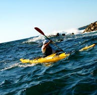 Un ragazzo che ha noleggiato un kayak da mare nel golfo di Porticcio con Cors'Aventure sta salutando un peschereccio.