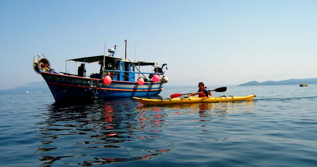 Un homme qui a loué un kayak de mer dans le golfe de Porticcio avec Cors'Aventure salut un bâteau de pêche.