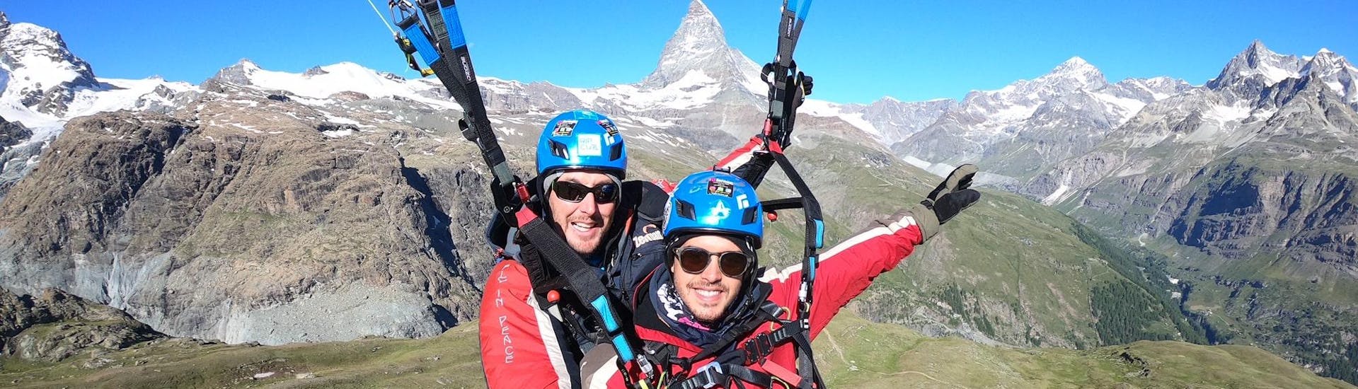 A paragliding guide from Matterhorn Paragliding with a man paragliding in the mountains above Zermatt. 