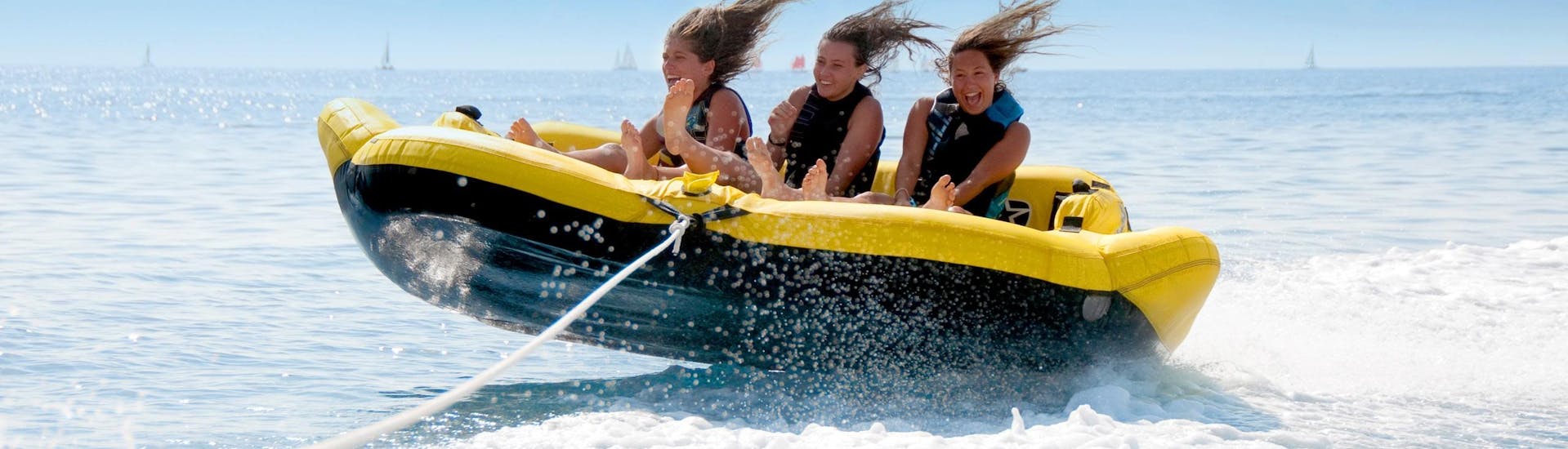 Trois jeunes filles s'amusent comme des folles sur une bouée gonflable dans la Baie des Anges avec Nikaïa Watersports à Nice.