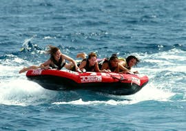 A group of friend is laughing on a towable tube in the Baie des Anges thanks to Nikaia Watersports in Nice. 