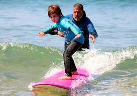 An instructor is supporting a young boy during a private surfing lesson on Matosinhos beach near Porto with Fish Surf School. 
