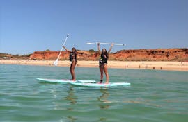 Twee meisjes op SUP boards van Nauticdrive op het strand van Praia da Rocha Baixinha. 