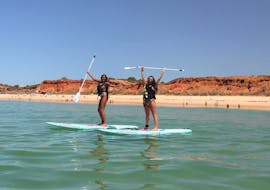 Two girls on SUP boards from Nauticdrive on Praia da Rocha Baixinha beach. 