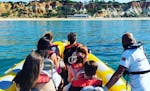 A group of people in a Nauticdrive boat on their tour to the Benagil cave in front of Praia da Rocha beach.
