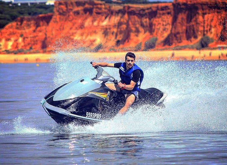 A young man on a Nauticdrive jet ski rides in the Atlantic Ocean in front of the Praia da Rocha beach. 