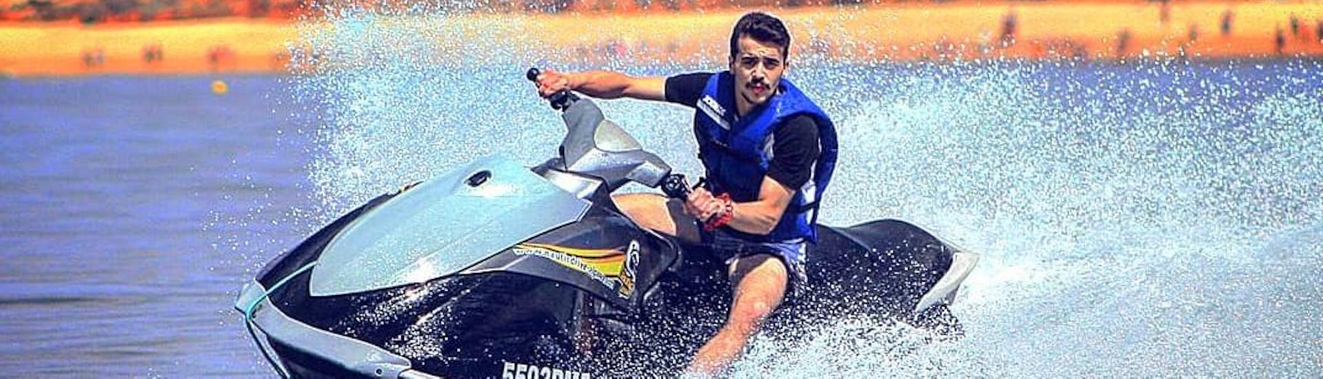 A young man on a Nauticdrive jet ski rides in the Atlantic Ocean in front of the Praia da Rocha beach. 