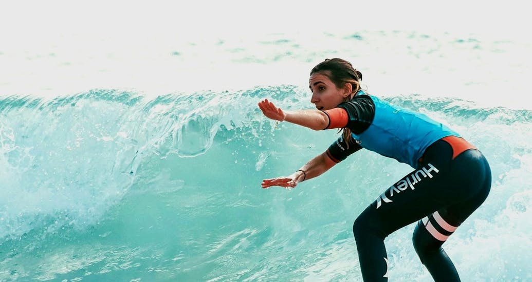 Une surfeuse se concentre sur sa technique alors qu'elle prend une vague lors de son cours de surf sur la plage du Penon avec Surf Evolution Seignosse. 
