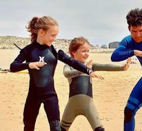Two little girls are learning the basics of surfing with their instructor during a surf lesson for kids on Penon Beach with Surf Evolution Seignosse.