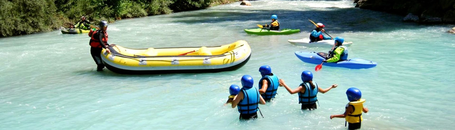 Gezinnen en kinderen steken de rivier de Guisane over om aan boord te gaan van hun raft tijdens hun ontdekkingstocht met Piraft Rafting Serre Chevalier.
