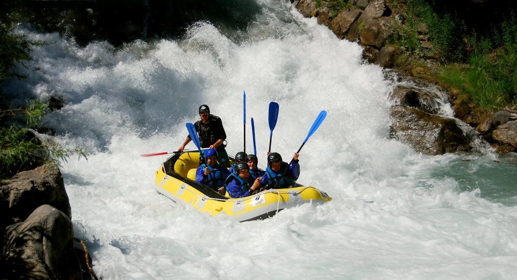 Un gruppo di ragazzi ha appena superato una cascata durante l'avventuroso tour di rafting sul fiume Guisane di Piraft Rafing Serre-Chevalier.