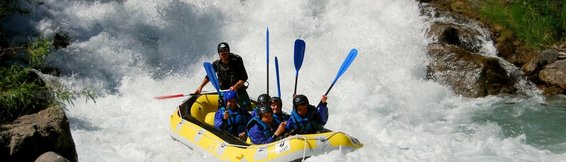 Un grupo de tíos acaba de superar una cascada durante el aventurero recorrido de rafting por el río Guisane de Piraft Rafing Serre-Chevalier.