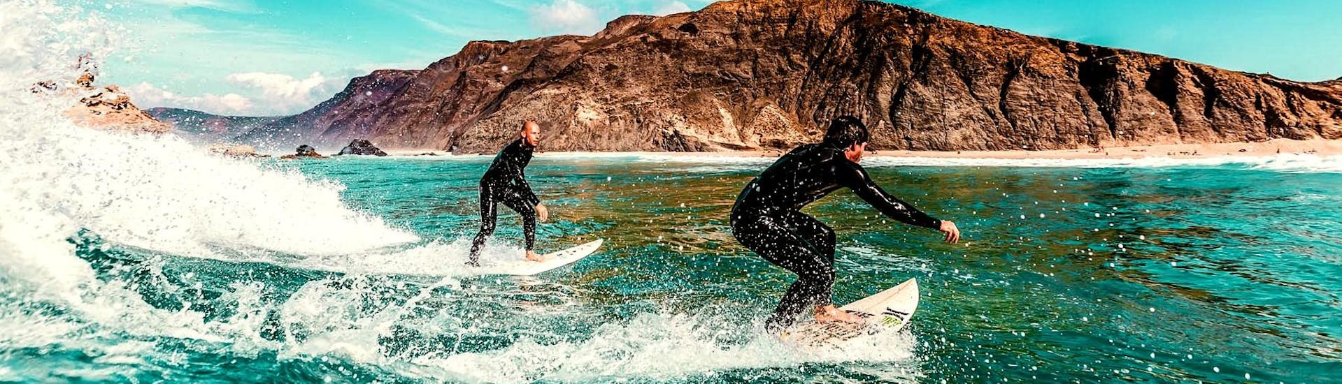 Dos chicos montan las olas durante una lección privada de surf cerca de Lagos con Tiny Whale Surf Lodge.