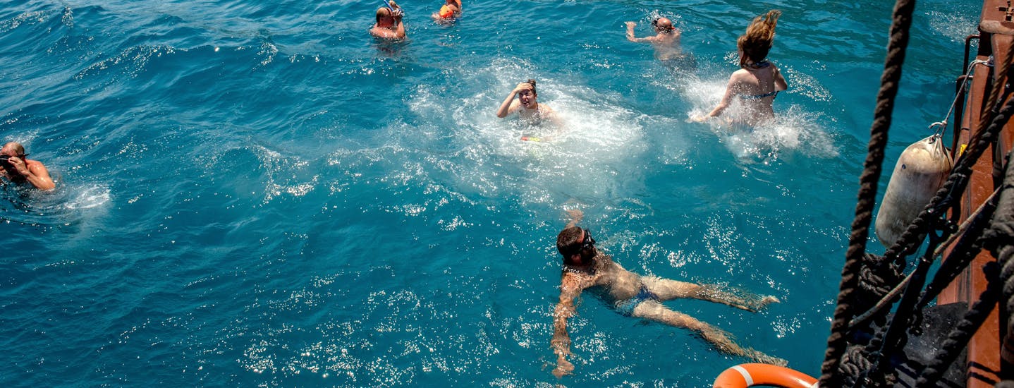 Persone che nuotano accanto alla barca durante la gita in barca dei pirati nella baia di Kefalas a Creta con Snorkeling with Dolphin Cruises. 