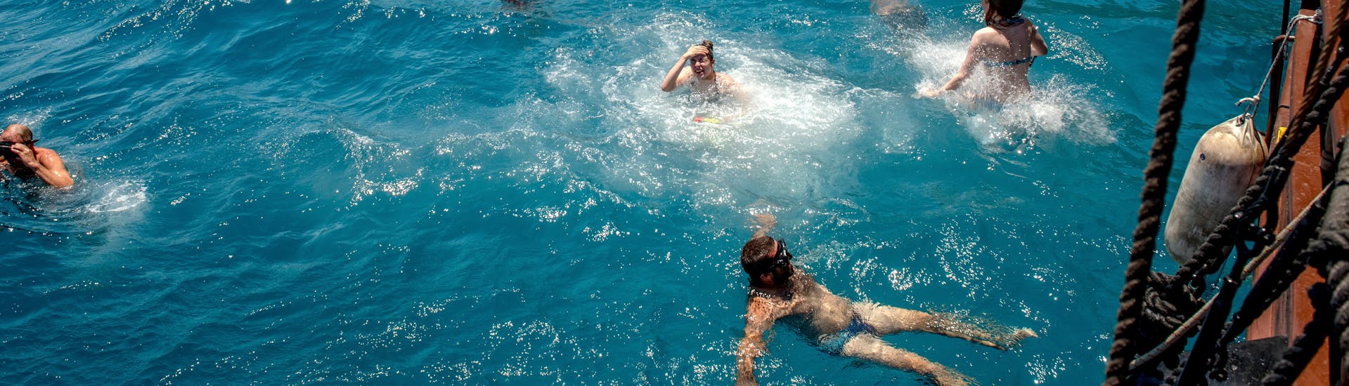 Gente nadando junto al barco durante el viaje en barco pirata a la bahía de Kefalas en Creta con Snorkeling with Dolphin Cruises. 