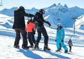 Un grupo de snowboarders está aprendiendo a hacer snowboard con sus clases (a partir de 8 años) para principiantes con ESI Alpe d'Huez - European Ski School.