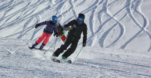Private Ski Lessons for Kids & Teens for Intermediate Skiers from Ski school Ski Zenit Saas-Fee An instructor of Ski School Zenit Saas-Fee is showing the parallel skiing technique to a kid during private kids ski lessons in Saas-Fee.