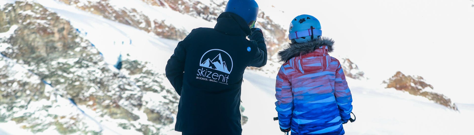 Un moniteur de la Ski School Zenit Saas-Fee présente le domaine skiable de Saas-Fee à un enfant pendant les cours particuliers de ski pour enfants à Saas-Fee.