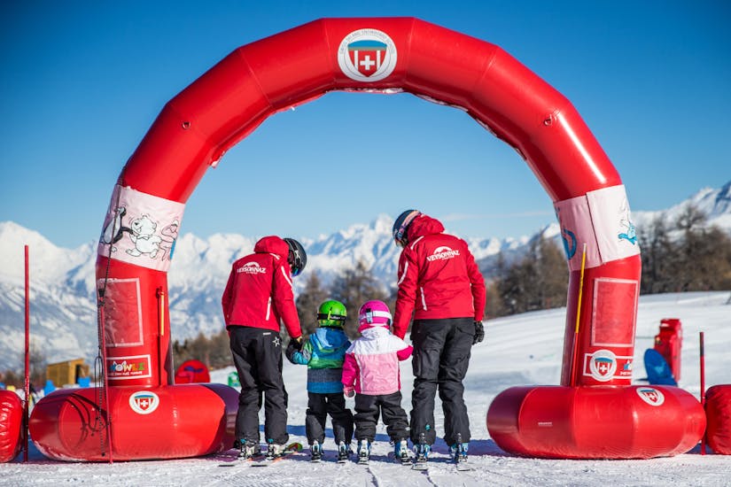 Twee instructeurs van de Zwitserse skischool Veyzonnaz helpen jonge kinderen hun eerste stappen op de ski's te zetten tijdens een privé skiles voor kinderen van 2,5 tot 5 jaar.