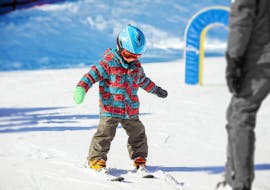 A young child is practicing his first steps on skis during the private ski lessons for kids (from 3 y.) with Family Ski School GO! Bad Gastein.