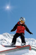 A young snowboarder is practicing freestyle tricks during the private snowboarding lessons (from 8 y.) for all levels with Family Ski School GO! Bad Gastein.