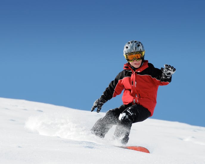 A young snowboarder is practicing his technique during the private snowboarding lessons (from 8 y.) for all levels with Family Ski School GO! Bad Gastein.
