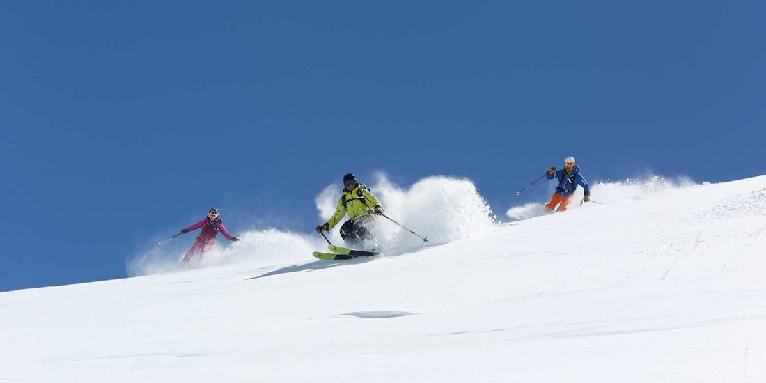 Twee skiërs volgen hun instructeur op de pistes tijdens een privé skiles voor volwassenen met Prosneige La Tania & Courchevel 1850.
