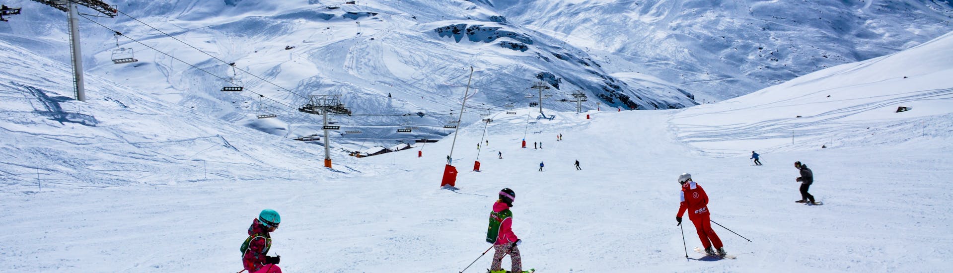 During a Super 6 kids ski lesson of ESF Val Thorens, young skiers descend a slope with their instructor.