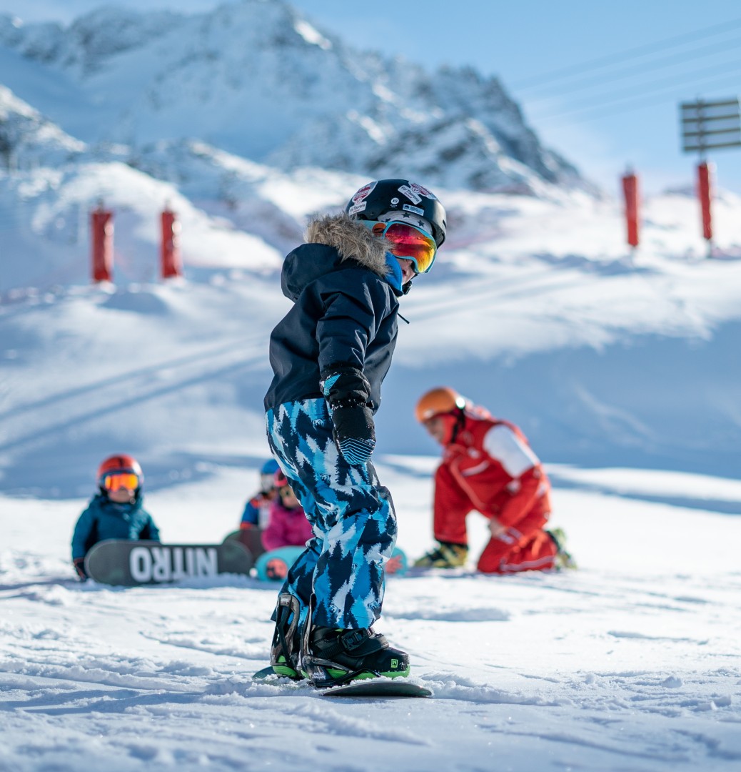 A child makes his first snowboard turns during a snowboarding lesson for kids for first timers with the ESF Val Thorens.