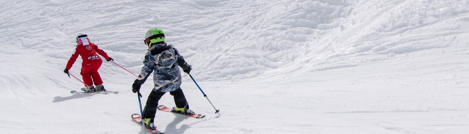 Un joven esquiador sigue a su instructor en las pistas durante una clase particular de esquí para niños, con la ESF Val Thorens.