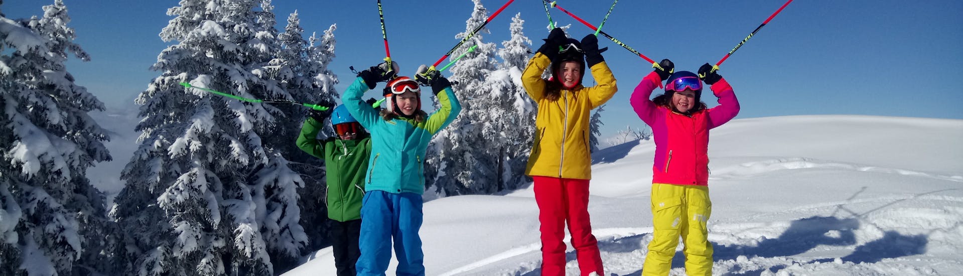 Unos niños en la nieve durante sus clases particulares de esquí para niños (a partir de 4 años) para todos los niveles, con la escuela de esquí Skiart en Kitzbühel.