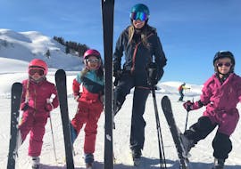 Een skileraar van Skiart Kitzbühel skischool met drie kinderen tijdens haar privé skilessen voor kinderen (vanaf 4 jaar) voor alle niveaus in Kitzbühel.