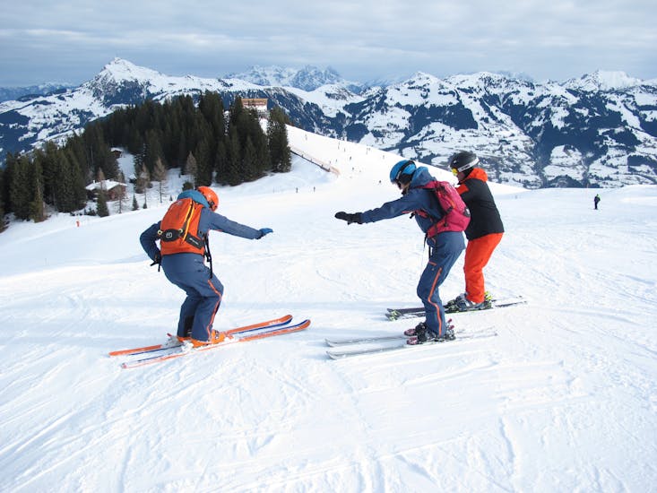 A ski instructor of the Skiart Kitzbühel ski school with students during the private ski lessons for adults of all levels in Kitzbühel.