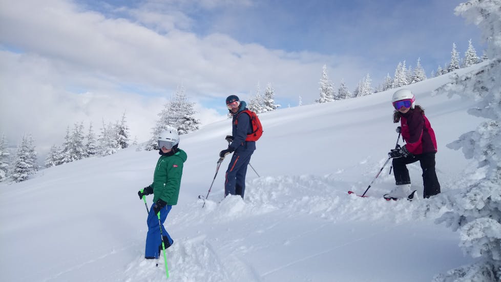 Kinder fahren mit ihrem Skilehrer von der Skischule SkiArt abseits der Piste während ihrer Freeride Stunde in Kitzbühel.